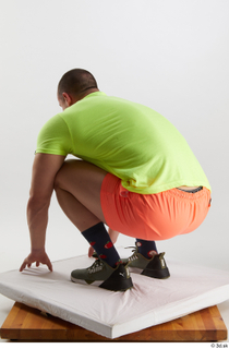 Joel  1 dressed green sneakers kneeling orange shorts sports…
